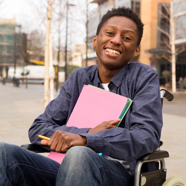 Boy in wheelchair holding school supplies